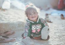 a little girl sitting on the ground with a stuffed animal