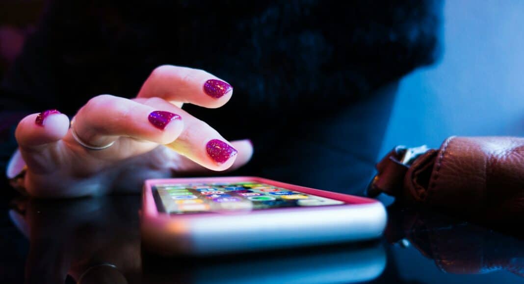 person using black smartphone with gray and pink case