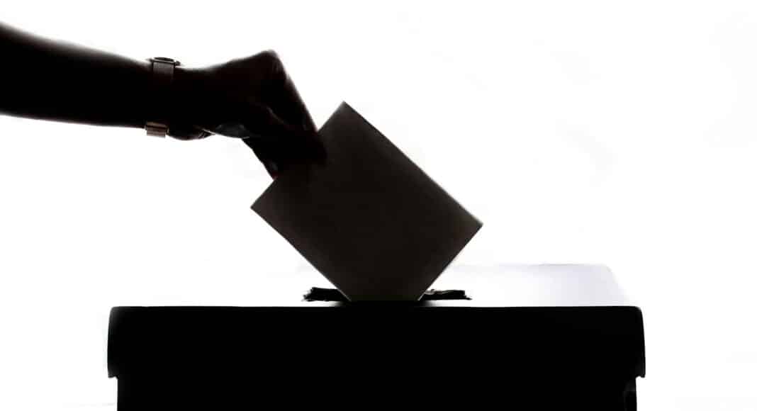 a person is casting a vote into a box