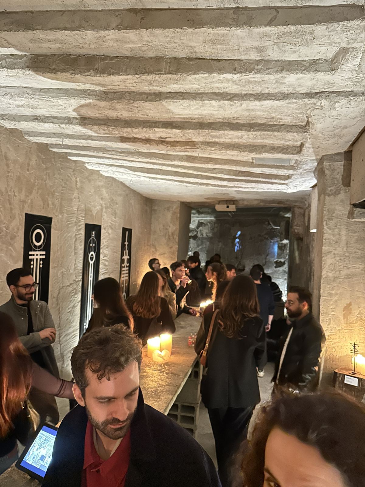 Des visiteurs découvrent les toiles, sculptures et projections de 55 dans la cave de Lucid Interval à Paris.